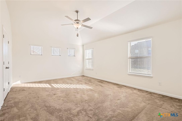 carpeted empty room with ceiling fan, a healthy amount of sunlight, and lofted ceiling