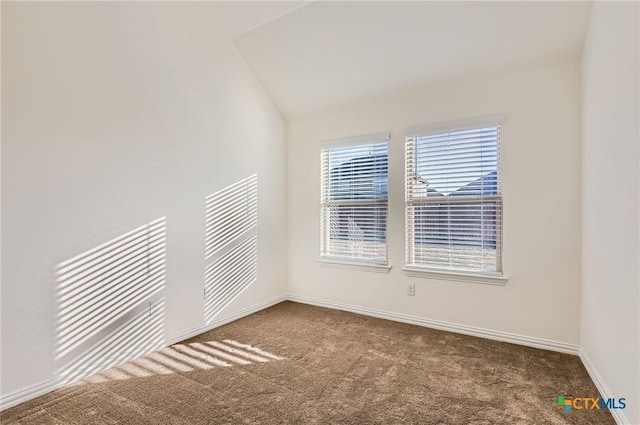 carpeted empty room featuring vaulted ceiling