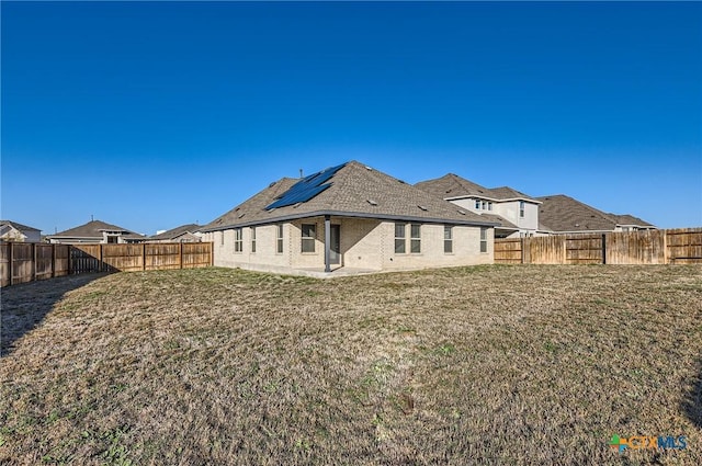 rear view of property with a lawn and solar panels