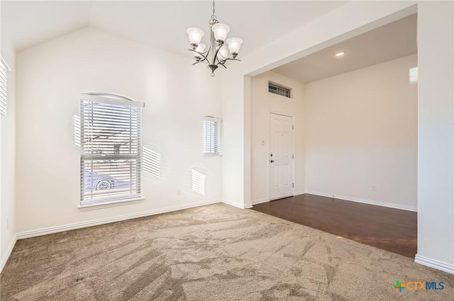 carpeted foyer with vaulted ceiling and a notable chandelier