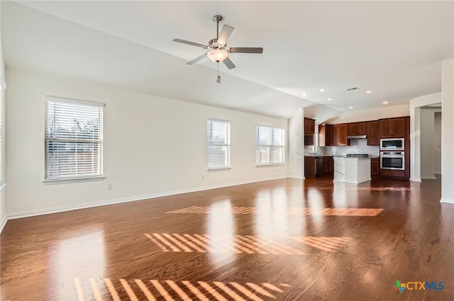 unfurnished living room with a healthy amount of sunlight, dark wood-type flooring, ceiling fan, and lofted ceiling