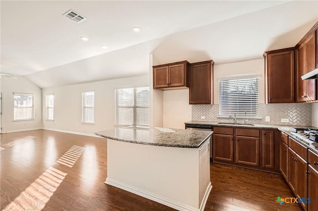 kitchen featuring backsplash, dark wood-type flooring, sink, vaulted ceiling, and light stone counters