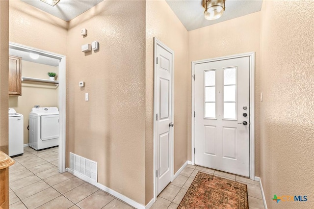 entryway with light tile patterned floors and independent washer and dryer