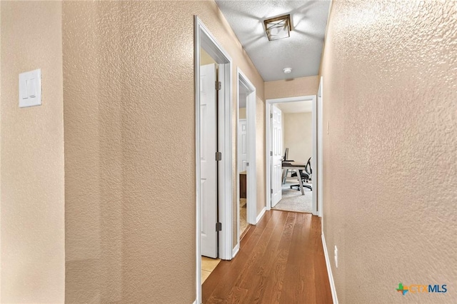 hall featuring a textured ceiling and light wood-type flooring