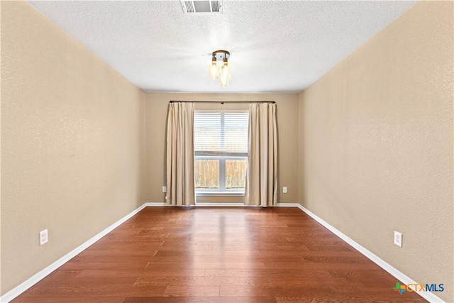 unfurnished room featuring hardwood / wood-style floors and a textured ceiling