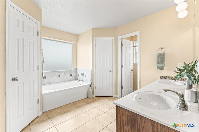 bathroom featuring tile patterned flooring, vanity, a washtub, and a textured ceiling