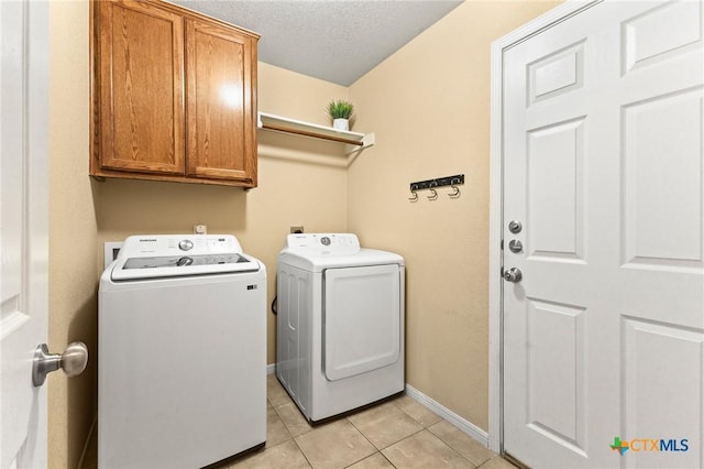 clothes washing area featuring cabinets, light tile patterned floors, washer and dryer, and a textured ceiling