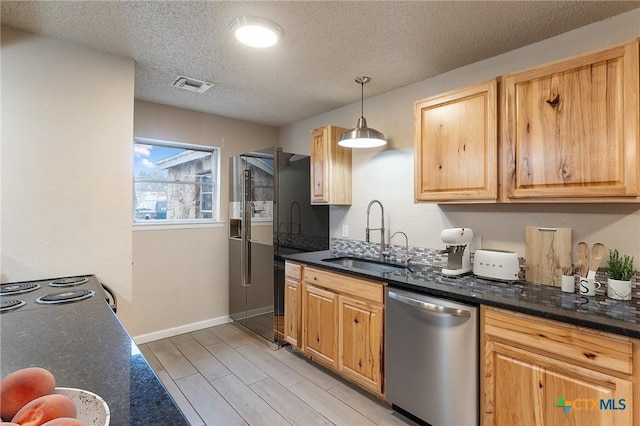 kitchen with visible vents, hanging light fixtures, black refrigerator with ice dispenser, stainless steel dishwasher, and a sink