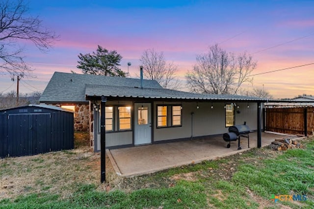 rear view of house featuring an outbuilding, a patio, a storage shed, fence, and stone siding