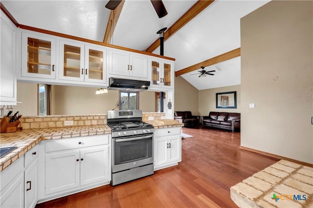 kitchen with vaulted ceiling with beams, white cabinetry, stainless steel gas range oven, ceiling fan, and light hardwood / wood-style floors