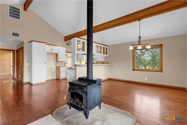 living room featuring beamed ceiling, dark hardwood / wood-style flooring, high vaulted ceiling, and a wood stove