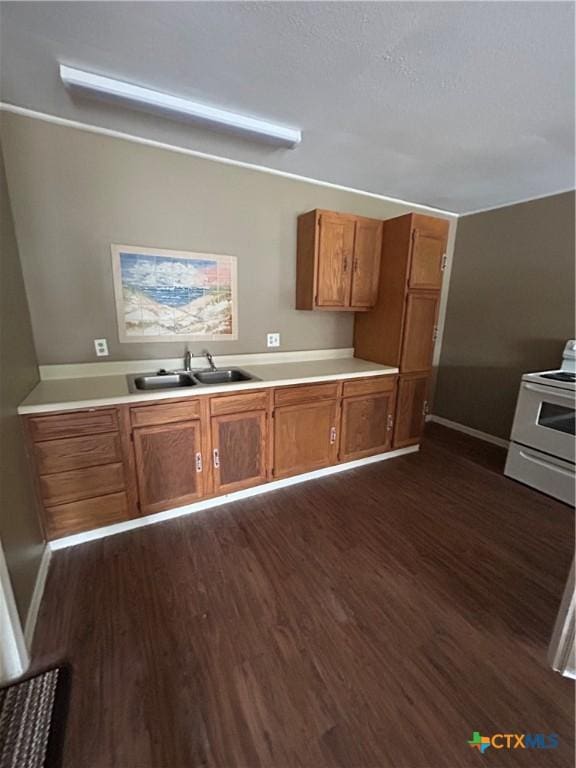 1511 E Constitution St, Victoria, TX 77901 - kitchen with electric range, a sink, dark wood-type flooring, and brown cabinetry