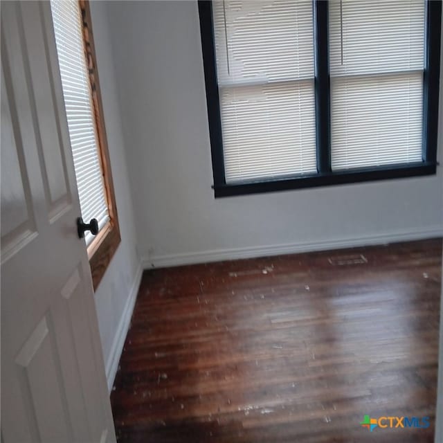 spare room featuring a wealth of natural light and dark hardwood / wood-style floors