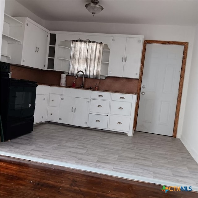 kitchen with white cabinetry, light wood-type flooring, black range oven, and sink