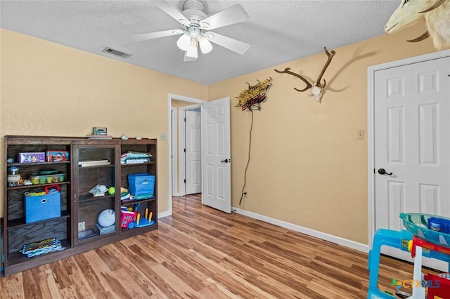404 Innwood Dr, Georgetown, TX 78628 - playroom with wood finished floors, a textured ceiling, baseboards, and ceiling fan