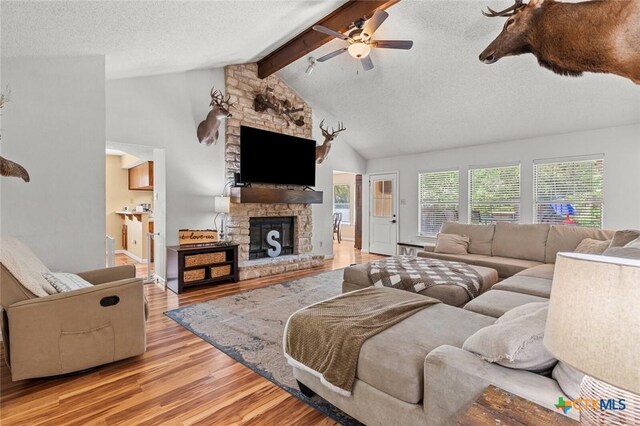404 Innwood Dr, Georgetown, TX 78628 - living area with a fireplace, ceiling fan, light wood-style flooring, beam ceiling, and a textured ceiling