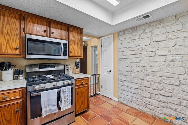 404 Innwood Dr, Georgetown, TX 78628 - kitchen with appliances with stainless steel finishes, brown cabinets, light countertops, light tile patterned floors, and baseboards