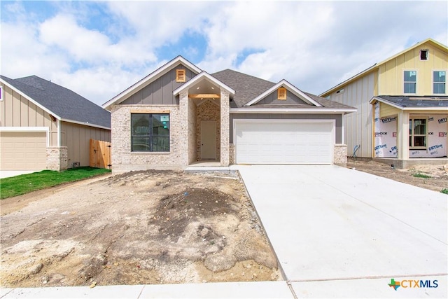 view of front of house with board and batten siding, an attached garage, driveway, and brick siding