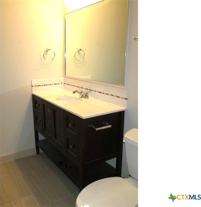 bathroom with decorative backsplash, vanity, and toilet