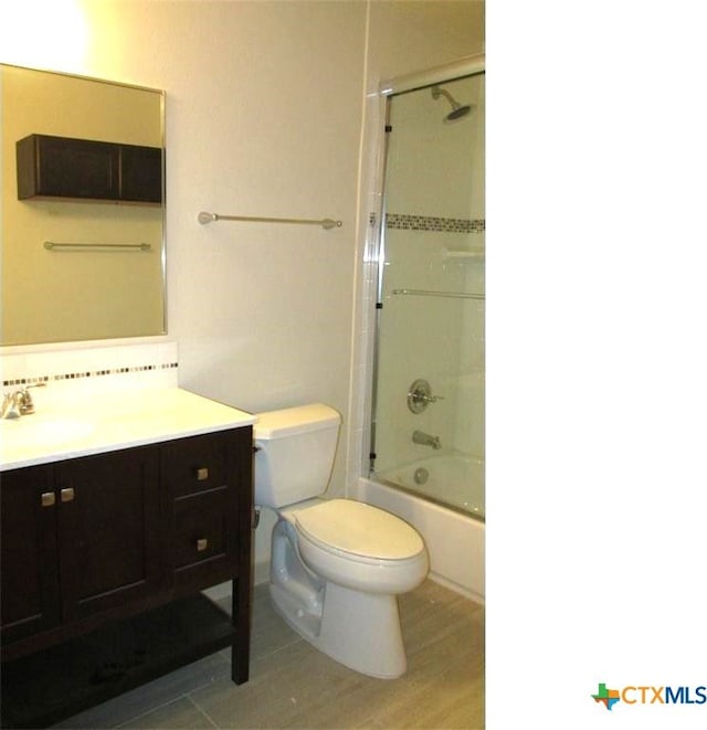 full bathroom with hardwood / wood-style flooring, vanity, tiled shower / bath combo, and toilet