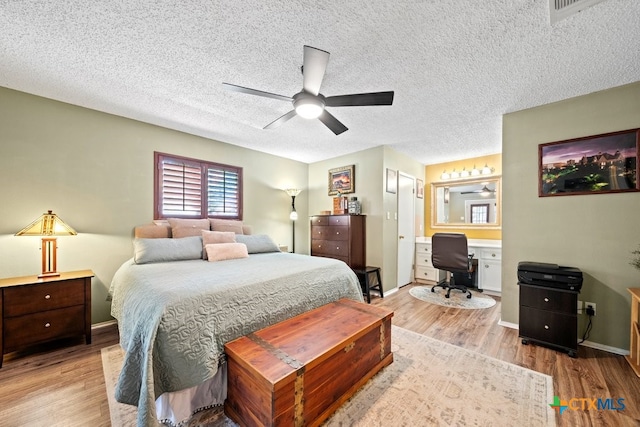 bedroom featuring connected bathroom, light wood-type flooring, a textured ceiling, and ceiling fan