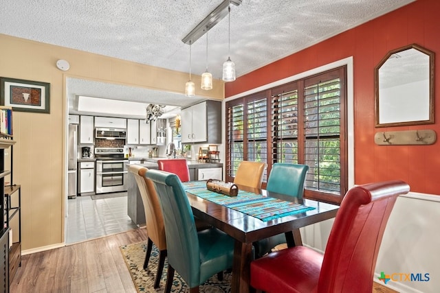 dining area featuring a textured ceiling, sink, and light hardwood / wood-style flooring