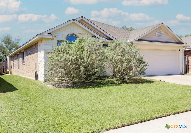 319 Silverado Trl, Victoria, TX 77901 - ranch-style home featuring concrete driveway, stone siding, an attached garage, a front lawn, and brick siding