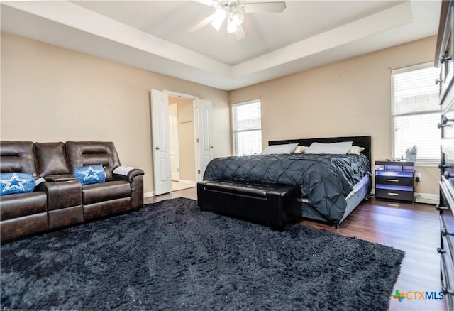 319 Silverado Trl, Victoria, TX 77901 - bedroom featuring dark wood-style floors, a tray ceiling, baseboards, and ceiling fan