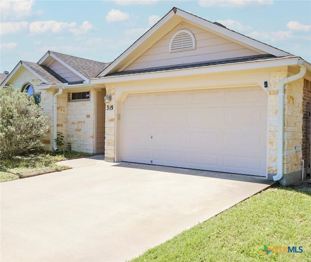 319 Silverado Trl, Victoria, TX 77901 - single story home featuring an attached garage, roof with shingles, driveway, and stone siding