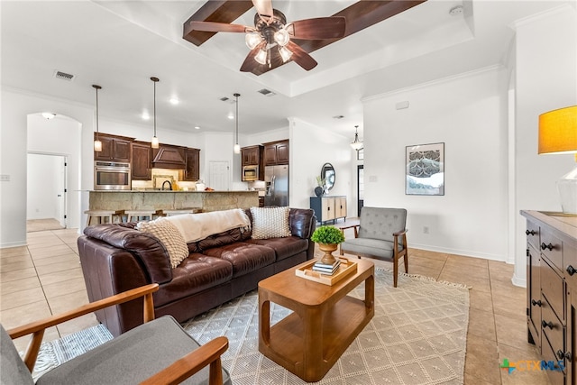 living room featuring light tile patterned floors, a tray ceiling, visible vents, and a ceiling fan