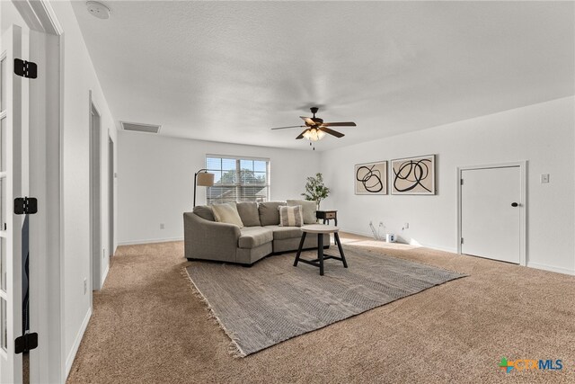 carpeted living room with ceiling fan, visible vents, and baseboards