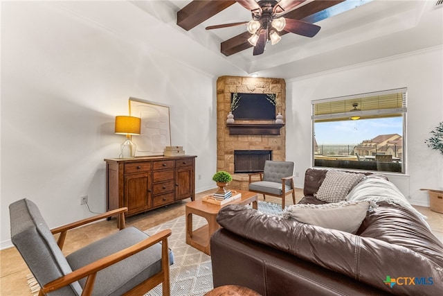 living room with ceiling fan, baseboards, beamed ceiling, and a stone fireplace