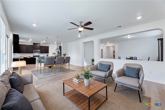 living room featuring light wood finished floors, visible vents, ceiling fan, recessed lighting, and arched walkways