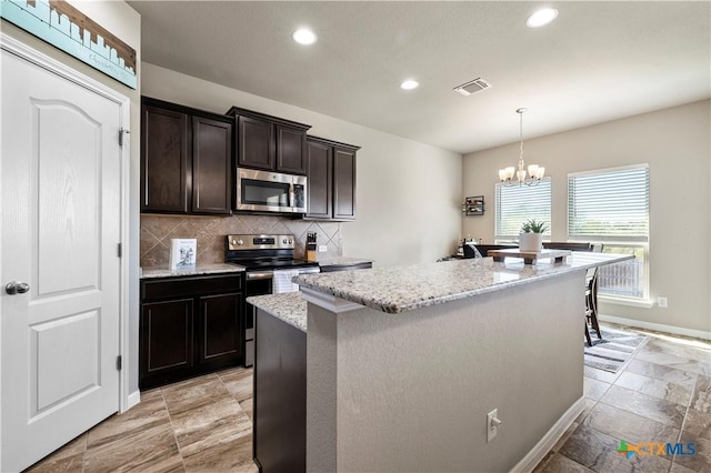 2206 Hayes St, Temple, TX 76502 - kitchen with appliances with stainless steel finishes, recessed lighting, decorative backsplash, a center island, and light stone counters