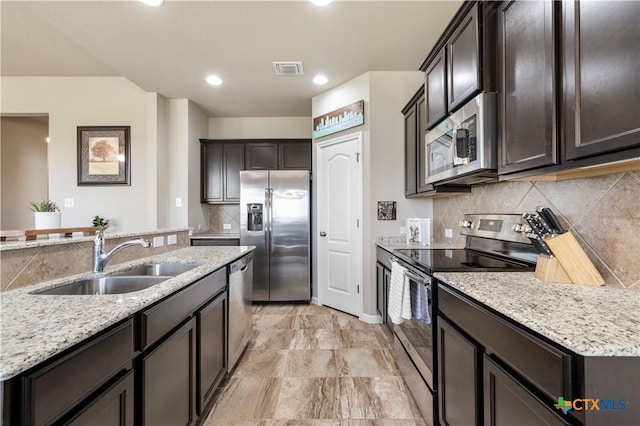 2206 Hayes St, Temple, TX 76502 - kitchen with stainless steel appliances, a sink, backsplash, dark brown cabinets, and light stone countertops