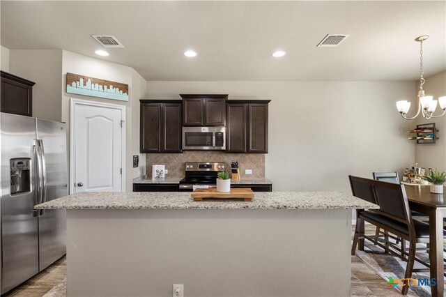 2206 Hayes St, Temple, TX 76502 - kitchen featuring stainless steel appliances, dark brown cabinets, a chandelier, a center island, and tasteful backsplash