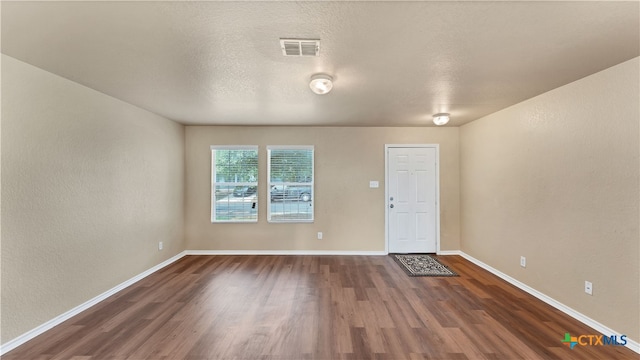 unfurnished room with dark wood-type flooring and a textured ceiling