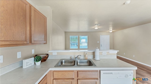 kitchen with dishwasher, kitchen peninsula, sink, light hardwood / wood-style flooring, and light brown cabinetry