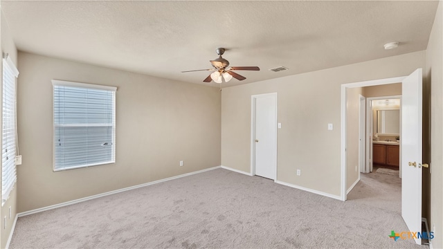 unfurnished bedroom featuring ceiling fan, a textured ceiling, and light carpet