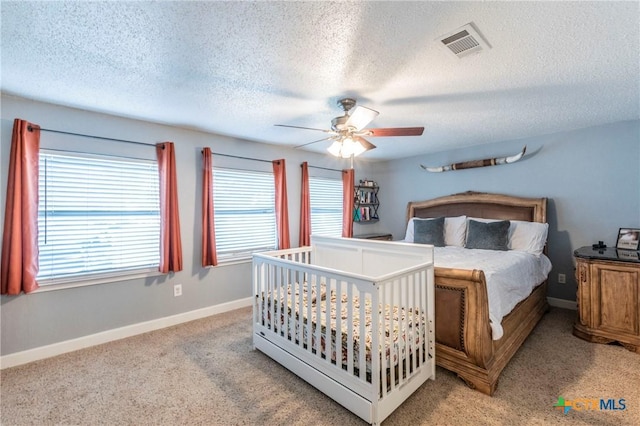 bedroom with baseboards, visible vents, ceiling fan, a textured ceiling, and light carpet