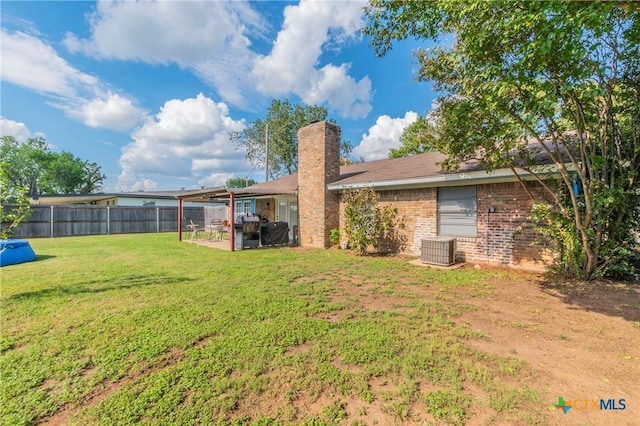 rear view of property with brick siding, fence, a lawn, a chimney, and a patio area