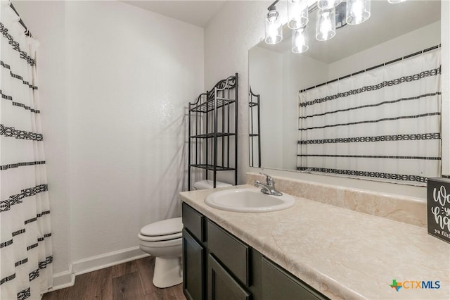 bathroom with curtained shower, baseboards, toilet, wood finished floors, and vanity