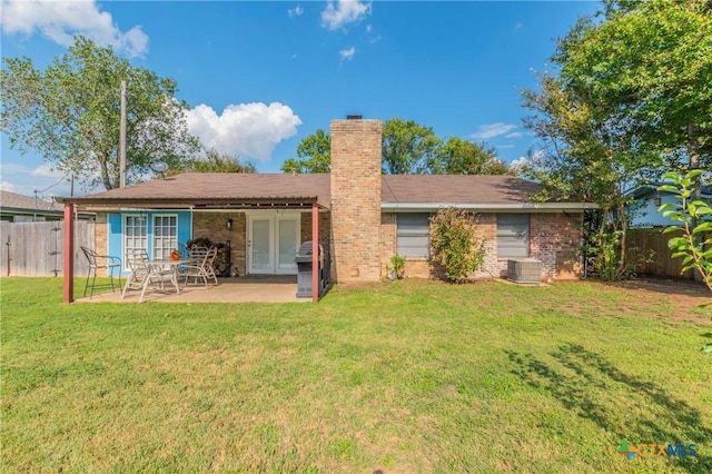 rear view of house with a lawn, a patio, a chimney, and a fenced backyard