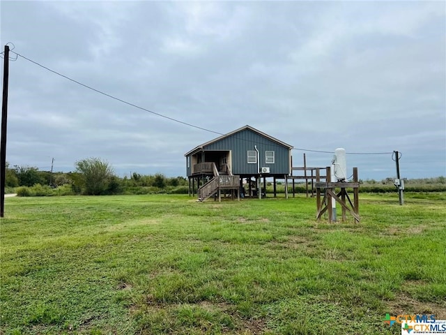 back of house with a rural view and a yard