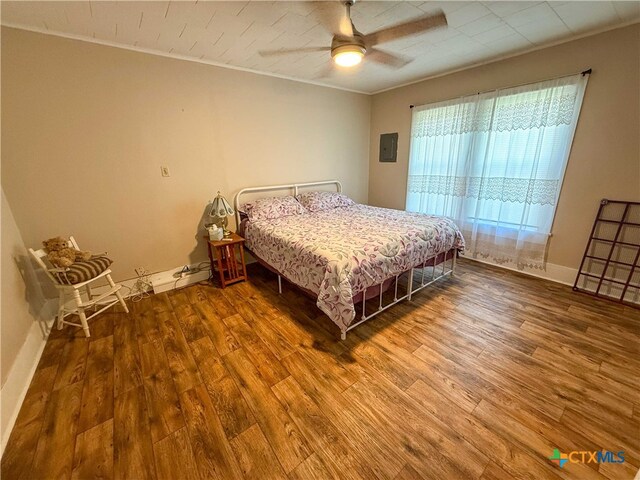 bedroom with baseboards, wood finished floors, a ceiling fan, and ornamental molding