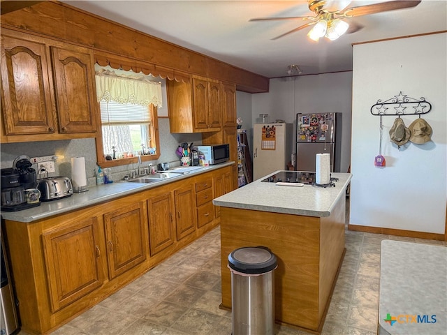 kitchen featuring brown cabinets, appliances with stainless steel finishes, a kitchen island, and a sink