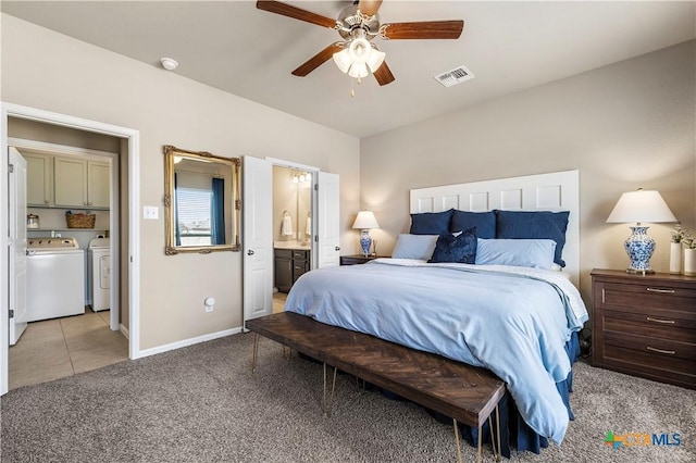 bedroom with light carpet, visible vents, baseboards, ensuite bathroom, and washing machine and dryer