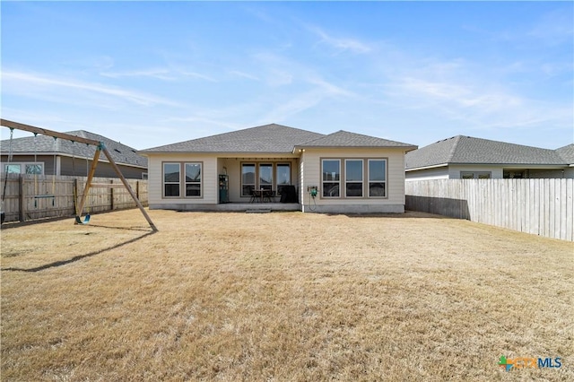 rear view of property featuring a lawn, a patio area, and a fenced backyard