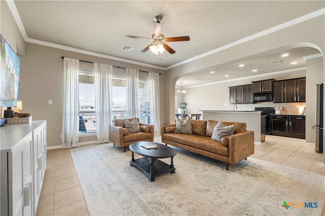 living room with light tile patterned floors, visible vents, arched walkways, and ornamental molding