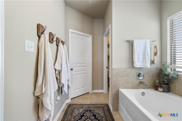 bathroom featuring baseboards, a bath, and tile patterned floors